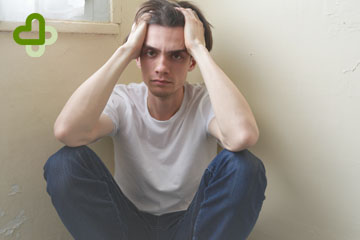 Мужчина сидит в углу комнаты